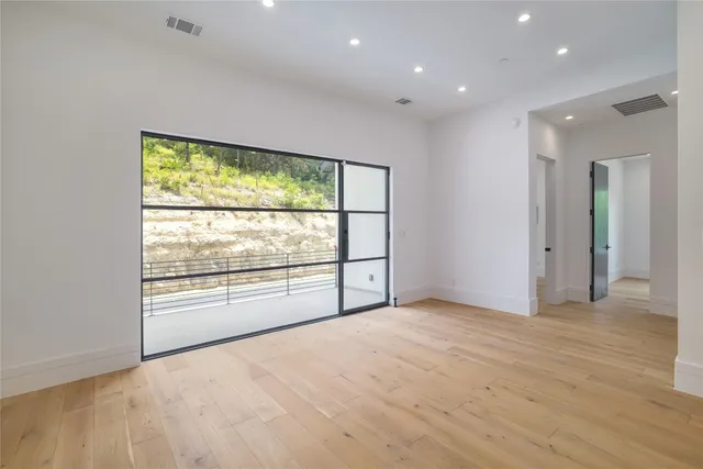 an empty room with wooden floor and windows