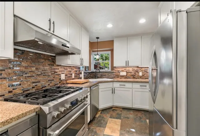a kitchen with stainless steel appliances granite countertop a stove a sink and a refrigerator