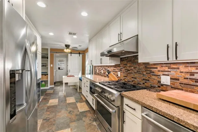 a kitchen with stainless steel appliances granite countertop a sink stove and refrigerator