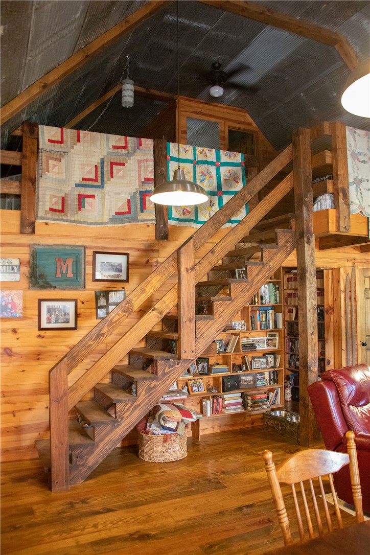 2026 Dry Creek Road St. Joe, AR 72675 - Photo 27 of 60 Exposed wood beam construction with wood-finish flooring, a built-in wooden staircase, and a corrugated metal ceiling