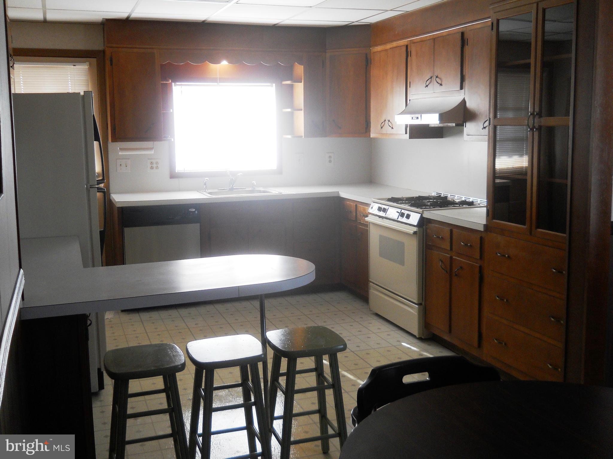 7616 Spruce Road Baltimore, MD 21222 - Photo 8 of 24 a kitchen with stainless steel appliances kitchen island a table chairs in it and wooden floors