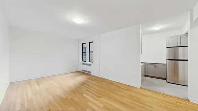 a view of empty room with wooden floor and window