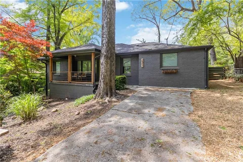 a view of a house with a yard and large tree