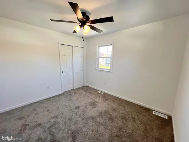 an empty room with a window and a fan