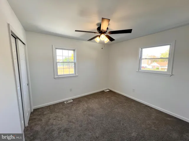 an empty room with windows and fan