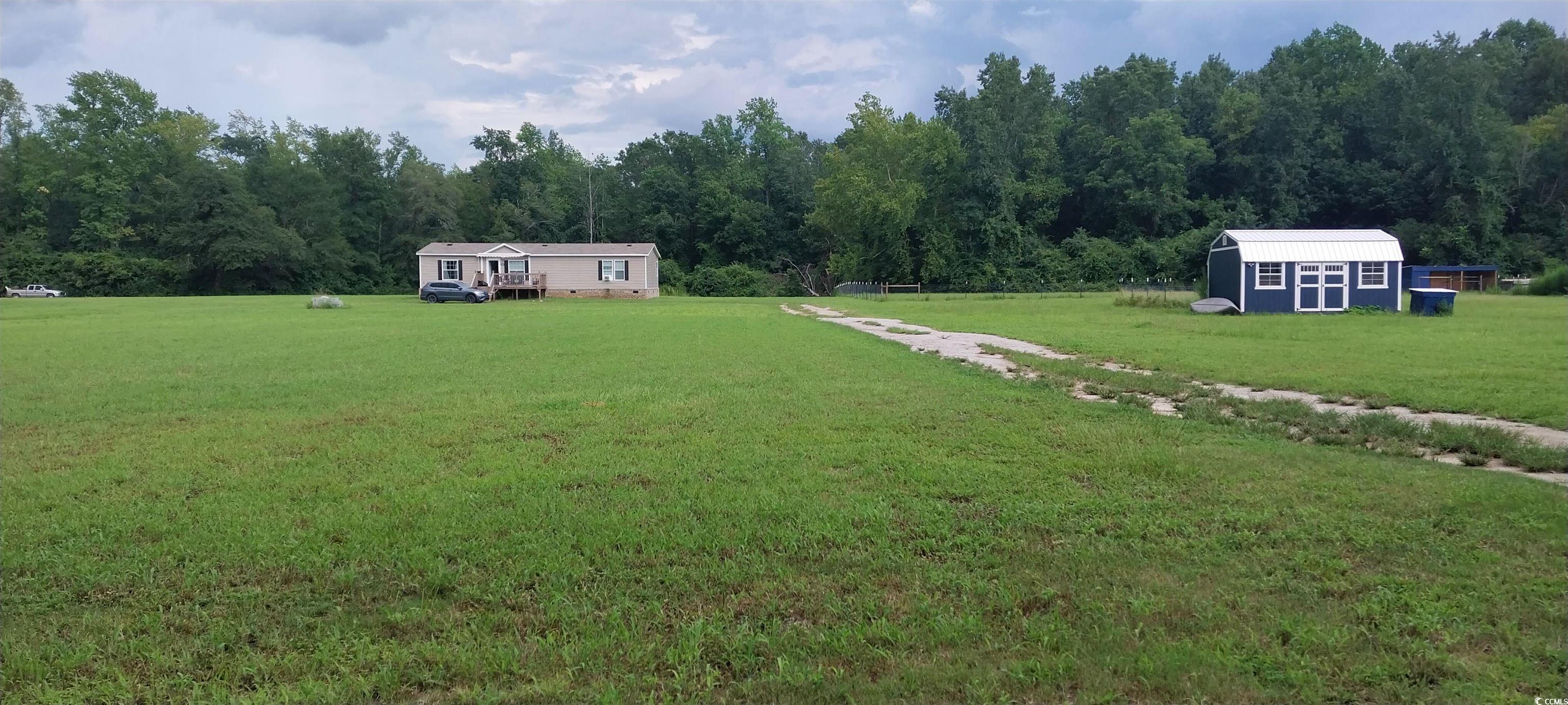 View of green lawn with a view of trees and a shed