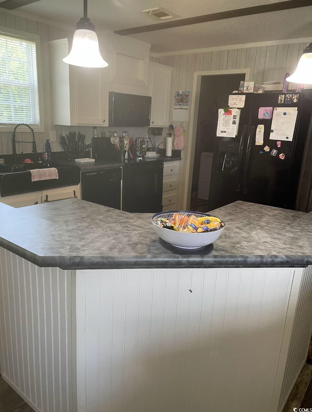 2470 Wigley Road Loris, SC 29569 - Photo 6 of 30 Kitchen featuring pendant lighting, white cabinets, black appliances, dark countertops, and wood walls