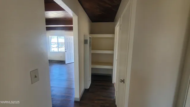 a view of a hallway with wooden floor and a bathroom