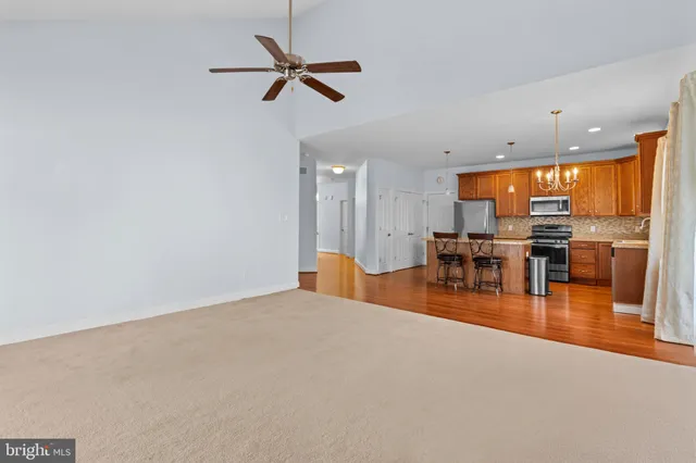 a view of a livingroom with chairs wooden floor and a ceiling fan