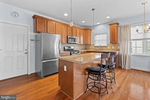 a kitchen with kitchen island a counter top space a sink stainless steel appliances and cabinets