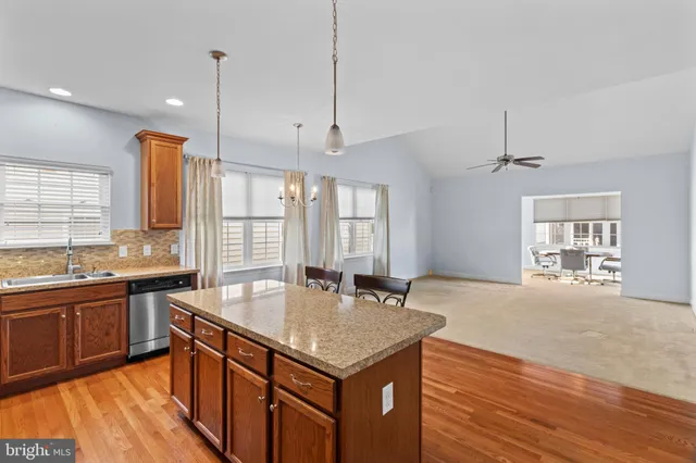 a kitchen with stainless steel appliances granite countertop a sink a stove and a wooden floors