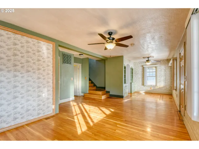 a view of a room with wooden floor and a ceiling fan