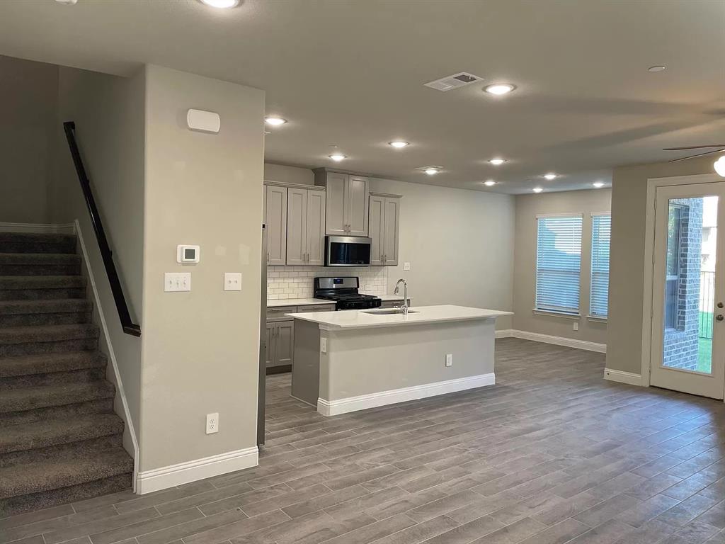 1752 Redding Street Allen, TX 75002 - Photo 4 of 24 Kitchen featuring appliances with stainless steel finishes, sink, a healthy amount of sunlight, backsplash, and a kitchen island with sink