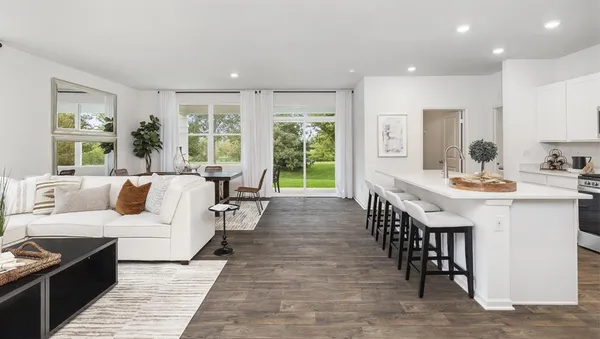 a living room with furniture a large window and wooden floor