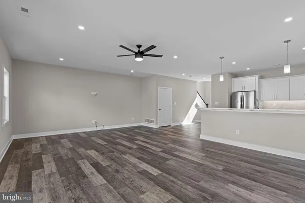 a view of an empty room with wooden floor and a ceiling fan