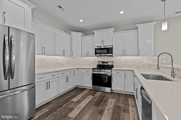 a kitchen with cabinets stainless steel appliances and sink