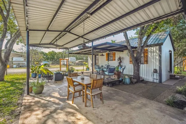 a view of a patio with table and chairs under an umbrella next to a yard
