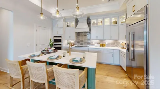 a kitchen with stainless steel appliances granite countertop a sink a stove a refrigerator cabinets and dining table