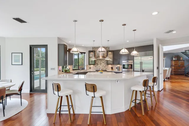 a kitchen with stainless steel appliances a dining table chairs stove and cabinets