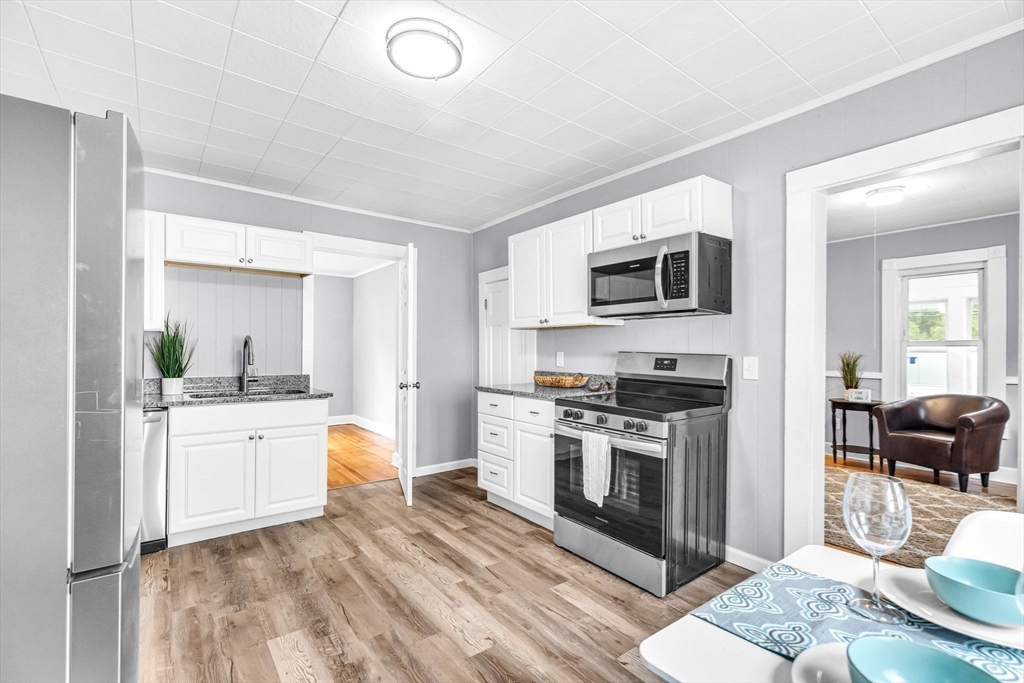125 Verge Street Springfield, MA 01129 - Photo 13 of 42 a kitchen with stainless steel appliances granite countertop a stove top oven a sink dishwasher a dining table and chairs with wooden floor