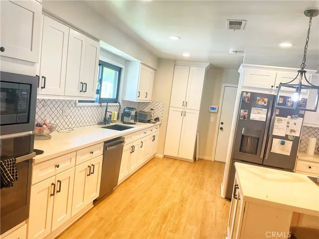 a large white kitchen with stainless steel appliances