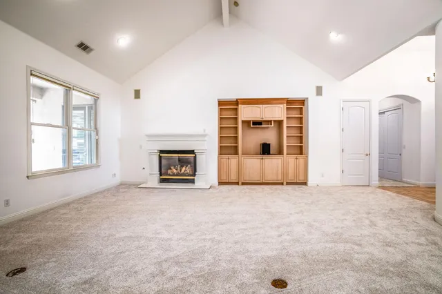 an empty room with windows and fireplace