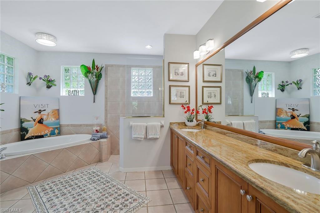 186 Muirfield Circle Naples, FL 34113 - Photo 18 of 32 a bathroom with a granite countertop sink a large mirror and a bathtub