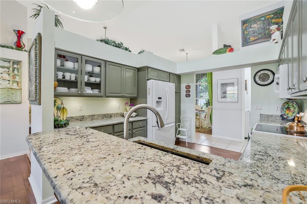 186 Muirfield Circle Naples, FL 34113 - Photo 10 of 32 a kitchen with granite countertop a sink a stove and cabinets