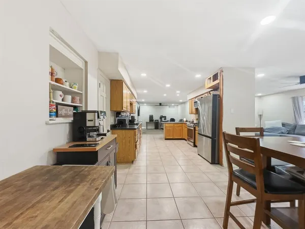 a kitchen with stainless steel appliances kitchen island granite countertop a refrigerator a stove a sink a dining table and chairs with wooden floor
