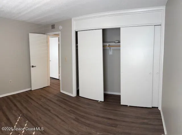 a view of an empty room with wooden floor and closet