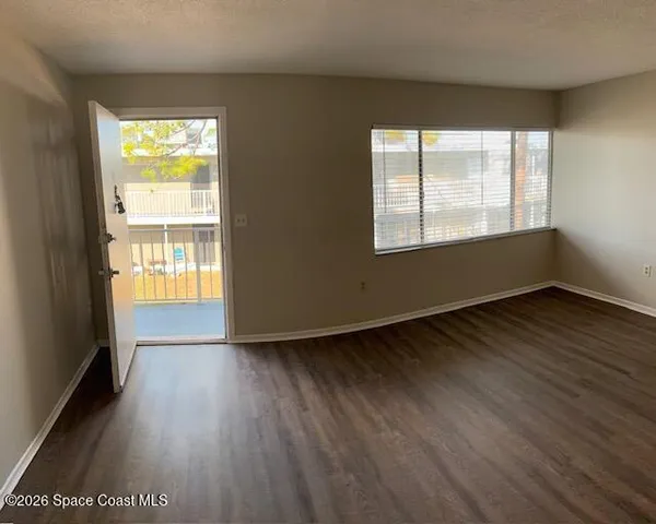 a view of an empty room and wooden floor and window