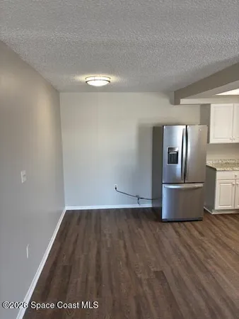 a view of kitchen with granite countertop cabinets and refrigerator