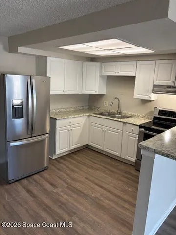 a kitchen with stainless steel appliances granite countertop a refrigerator a sink a stove and white cabinets