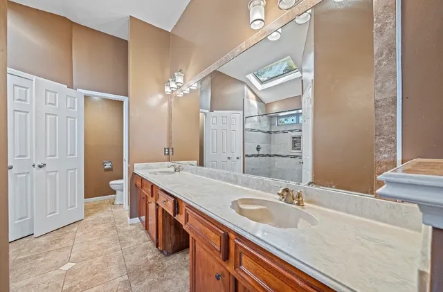 a spacious bathroom with a granite countertop sink a toilet a mirror and shower