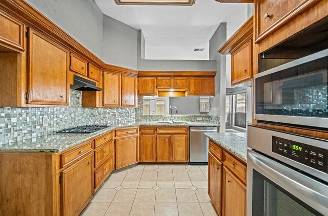 a kitchen with stainless steel appliances granite countertop a stove a sink and a microwave