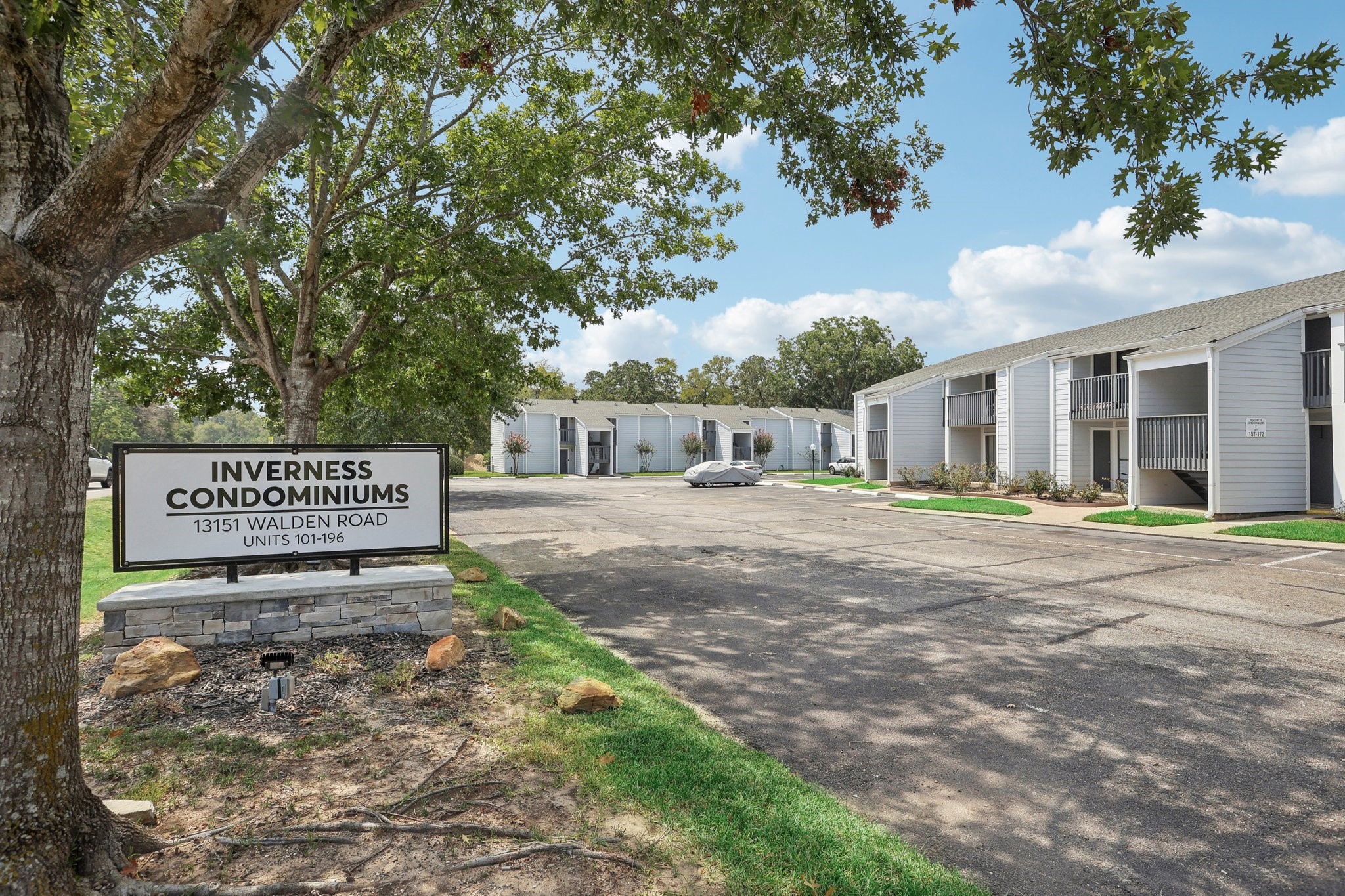 13151 Walden Road, Unit 136 Montgomery, TX 77356 - Photo 2 of 17 This is a photo of the Inverness Condominiums, located at 13151 Walden Road, showcasing units 101-196. Enjoy well-maintained two-story condominium buildings with external staircases and individual balconies, set in a serene environment with mature trees and a paved parking area.