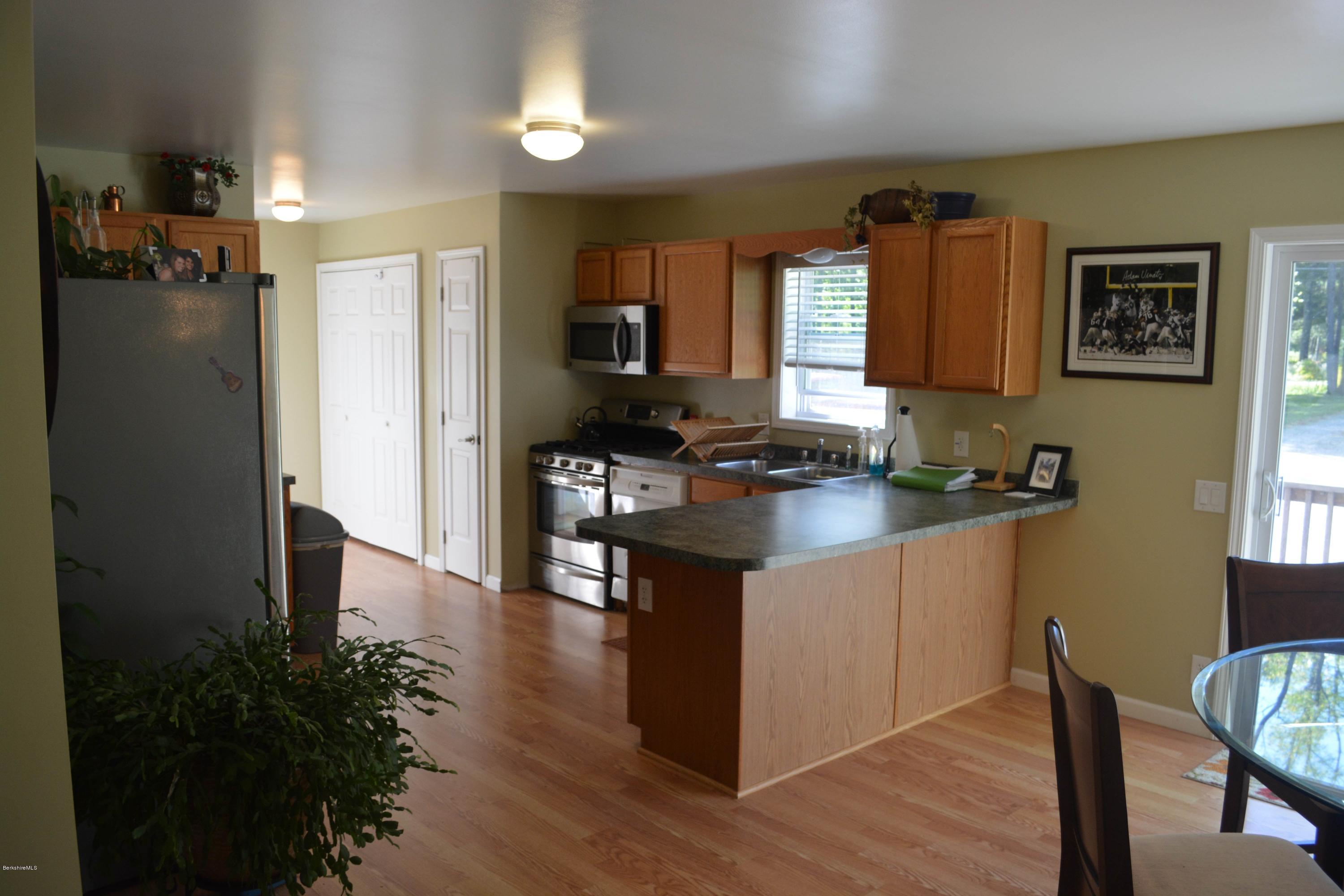220 Sandisfield Road Sandisfield, MA 01255 - Photo 5 of 30 a kitchen with granite countertop a refrigerator a stove a sink a dining table and chairs with wooden floor