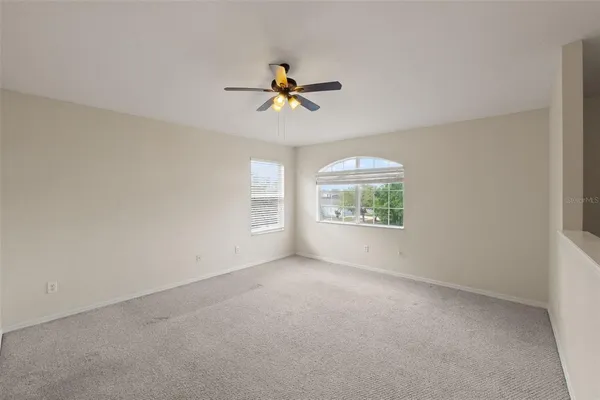 an empty room with windows and fan