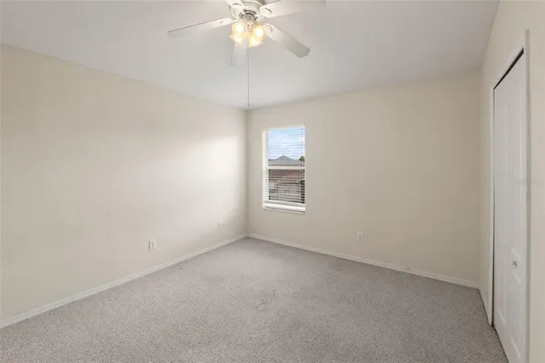 an empty room with a chandelier fan and windows