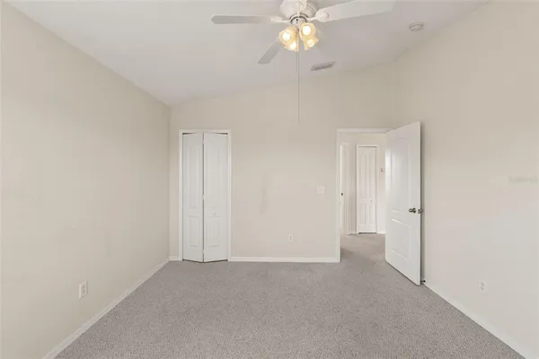 an empty room with a chandelier fan and closet area