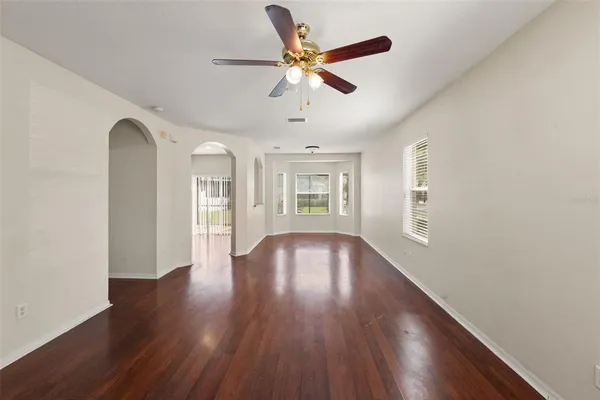 a view of an empty room with wooden floor and a window