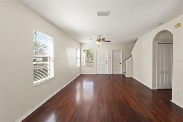 an empty room with wooden floor and windows