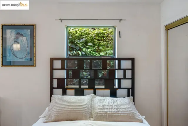 a bedroom with a bed and a large mirror next to a window