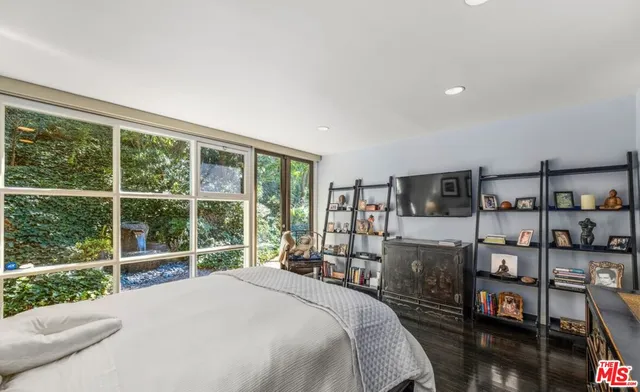a bedroom with a bed a large window and book shelf