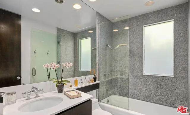 a bathroom with a bathtub shower sink and a mirror