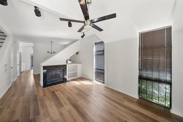 a view of a livingroom with wooden floor a ceiling fan and windows