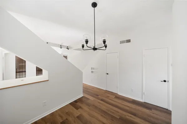 a view of a hallway with wooden floor and chandelier