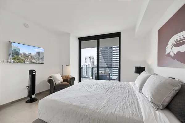 a bedroom with a bed a wall painting and a large window