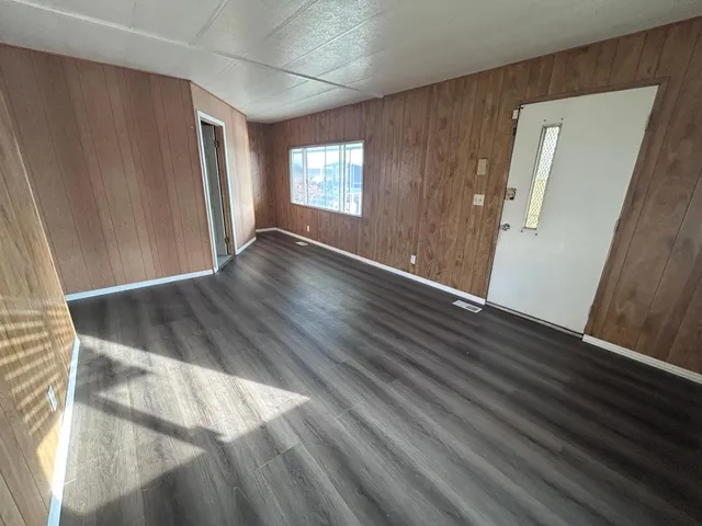 a view of an empty room with wooden floor and a window
