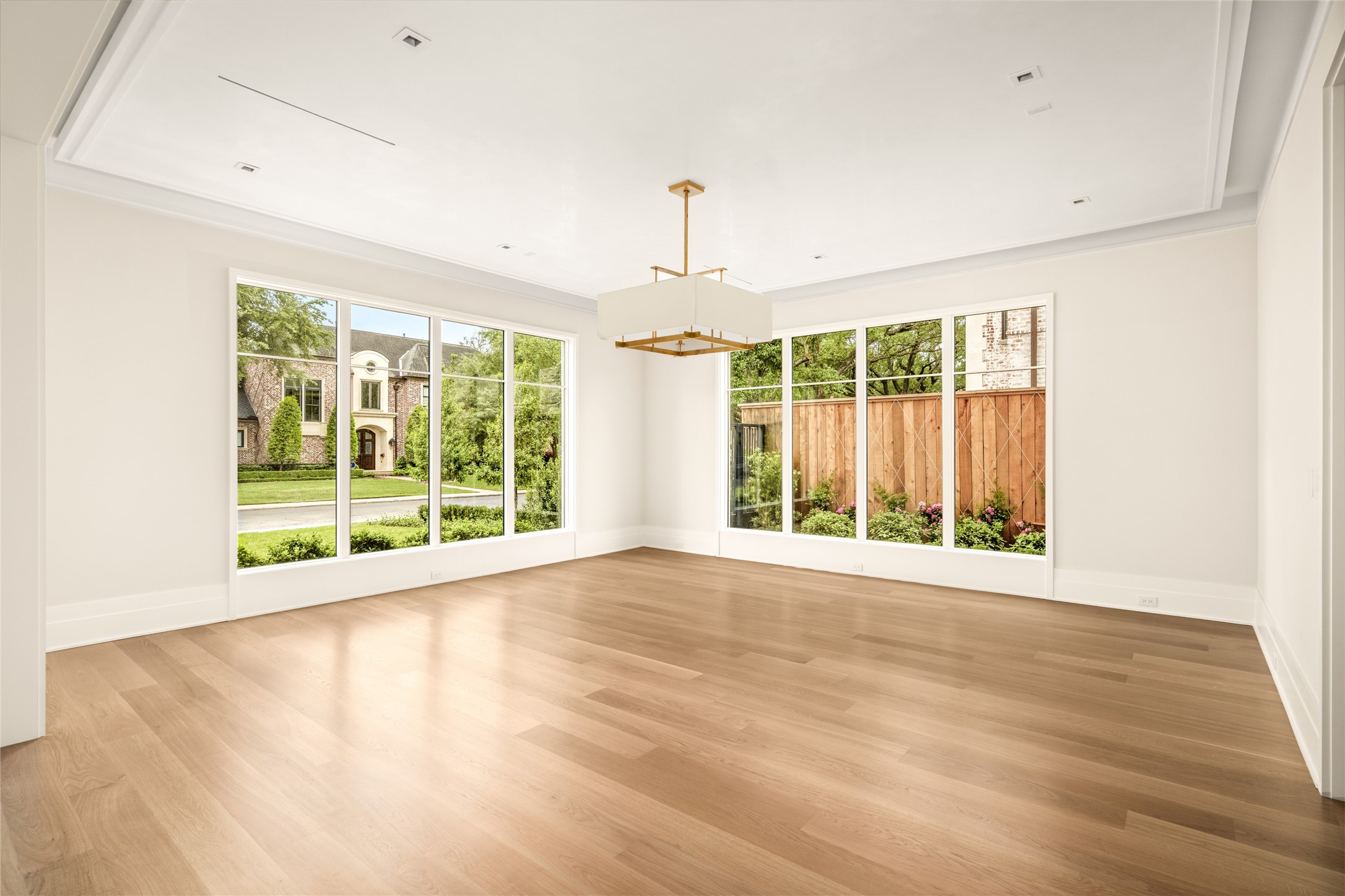 4006 Overbrook Lane Houston, TX 77027 - Photo 5 of 50 Formal living framed by floor-to-ceiling windows, featuring a tray ceiling with cove lighting, plaster-finished walls, and a statement Visual Comfort chandelier.